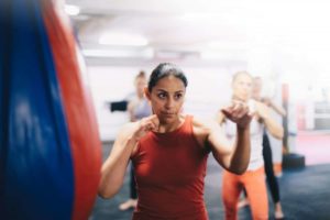 Kickboxing class with a woman in the foreground ready to perform an uppercut.