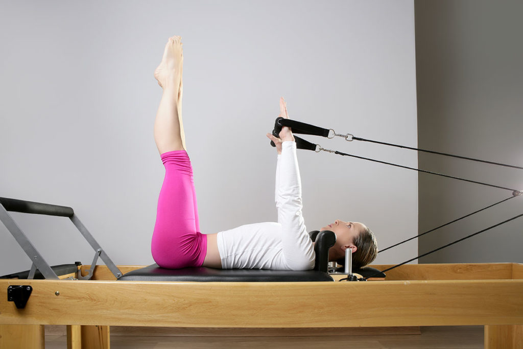 Woman performing Pilates training on a reformer.